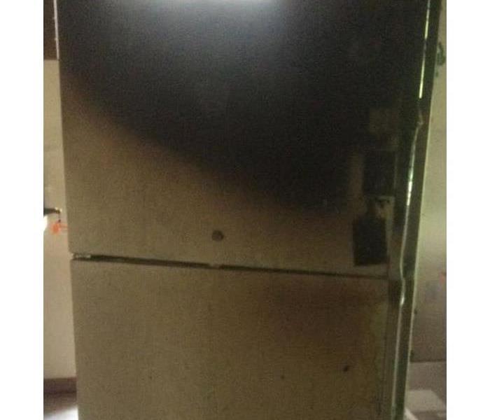 Top freezer refrigerator with burn and charred areas mainly on the top freezer.