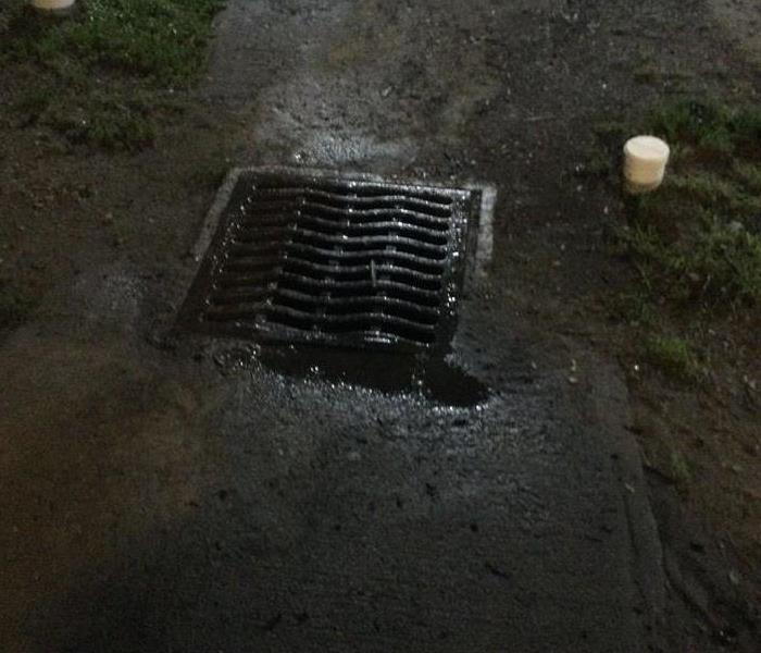 Storm sewer grate will puddles and wet concrete areas around it